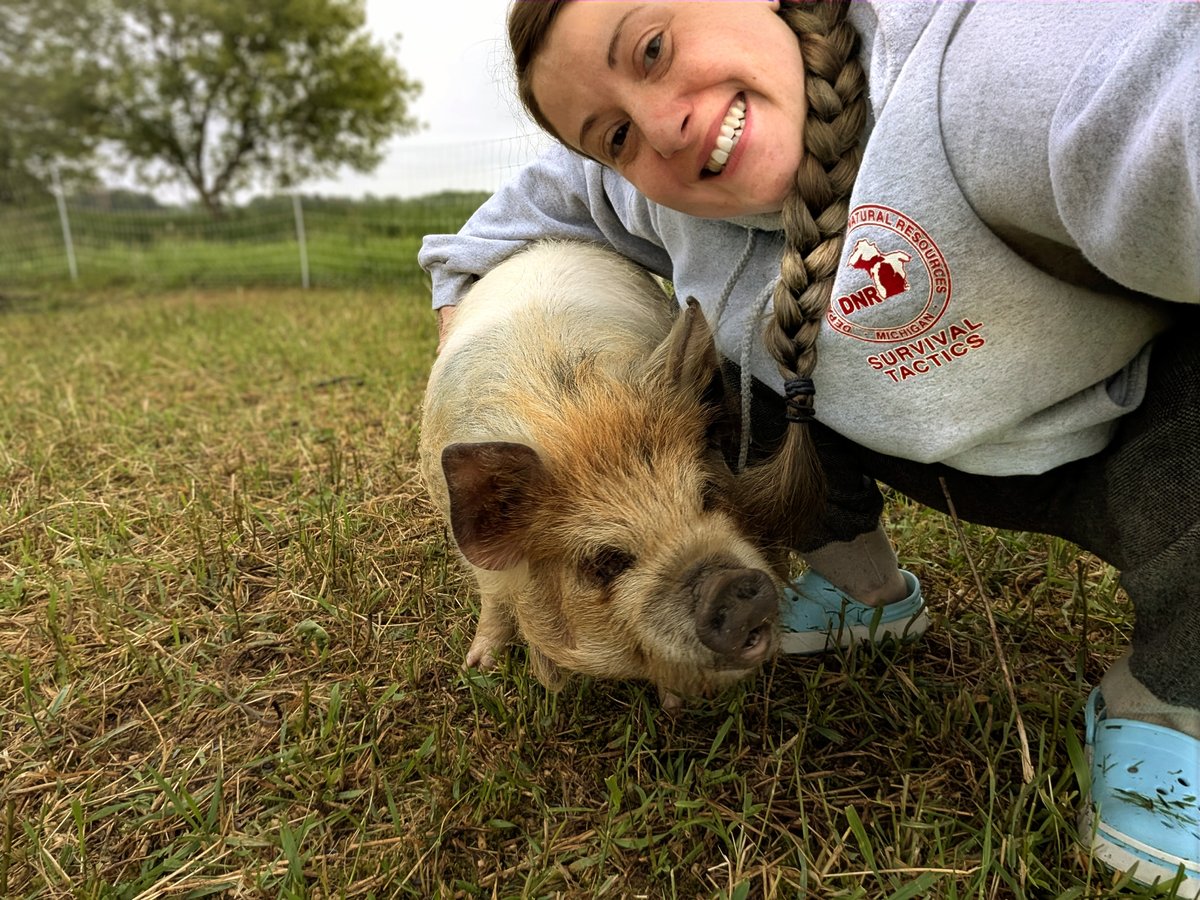 Casey kneeling beside a pasture pig